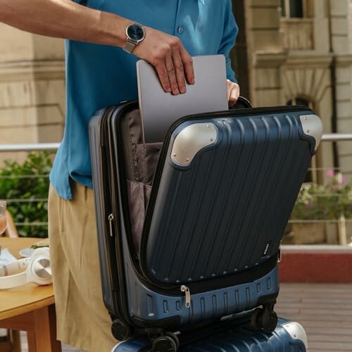 Person placing a laptop into a suitcase outdoors.