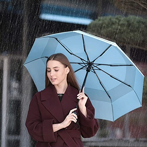 Woman holding a blue umbrella in the rain.